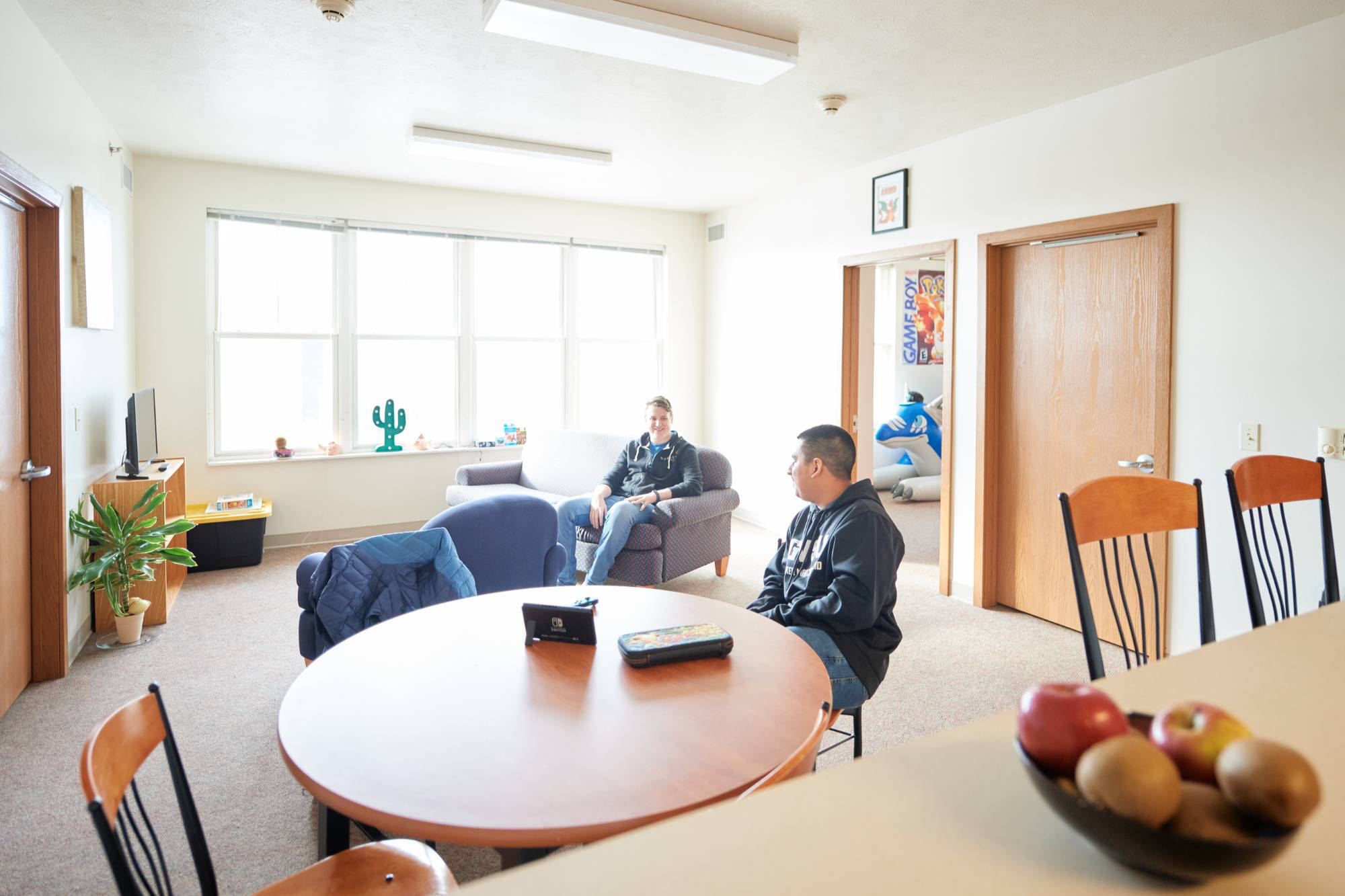 Two students talk in a light and homey Murray Living Center Apartment living room.